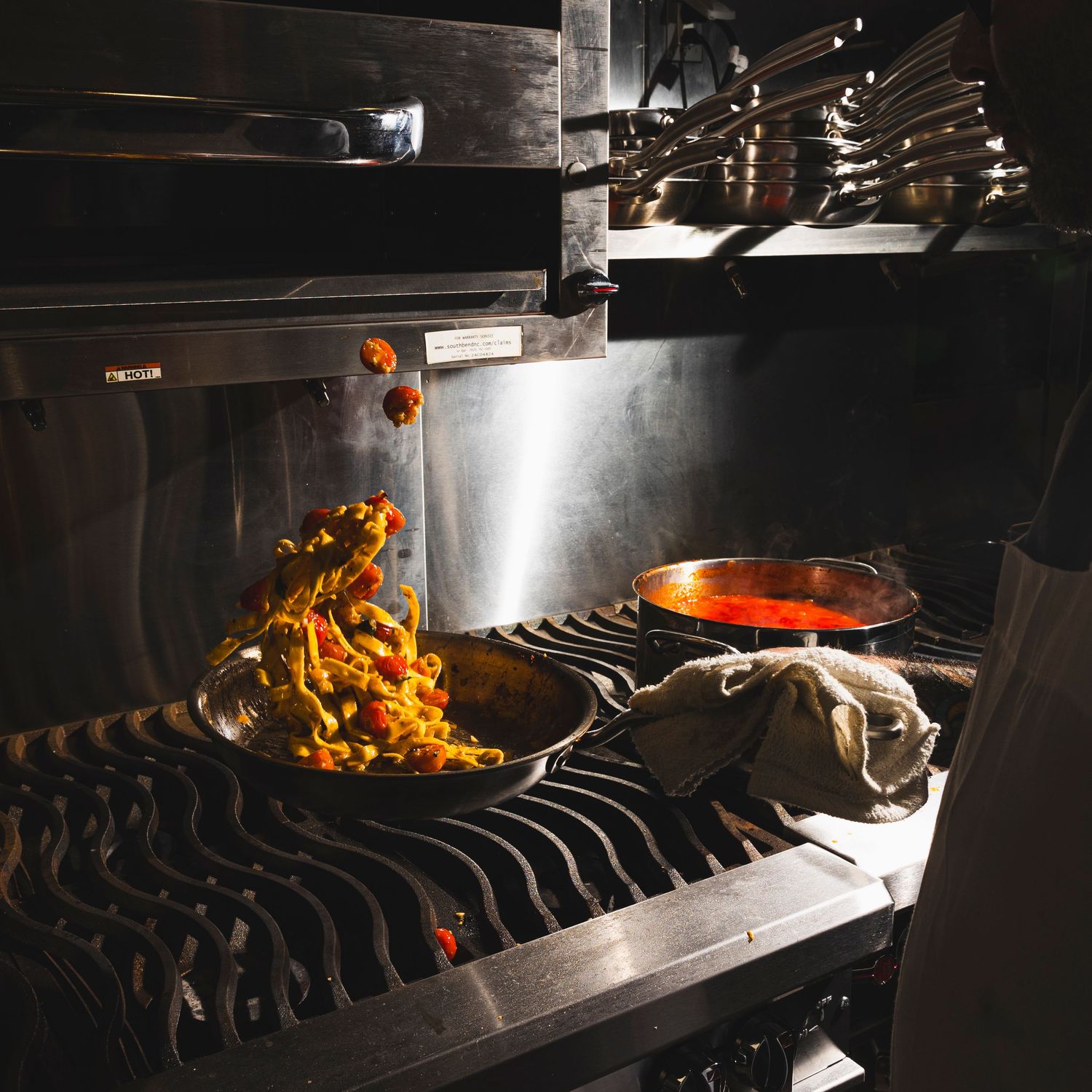 Restaurant kitchen grill with flames and smoke during dinner service.