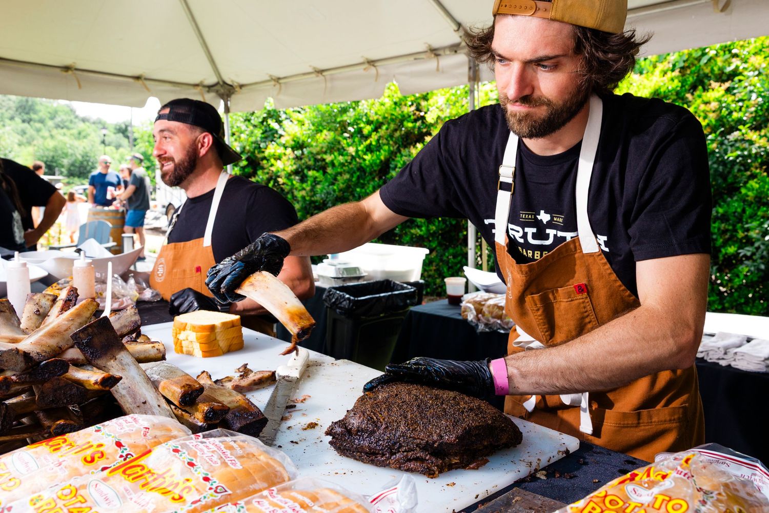 Chefs preparing meat and dishes at outdoor food festival.