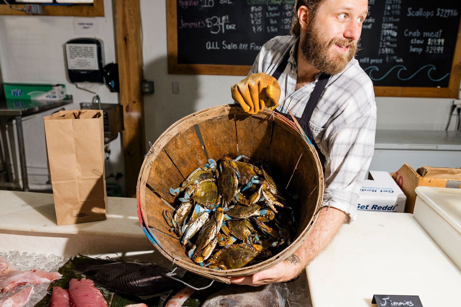 Wooden bushel basket filled with fresh oysters on a seafood shop counter.