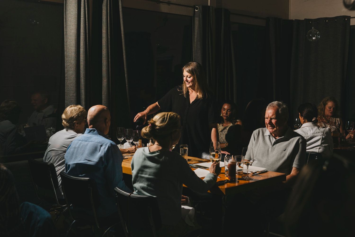 People dining together in a dimly lit restaurant setting at night with soft ambient lighting and tables in view.