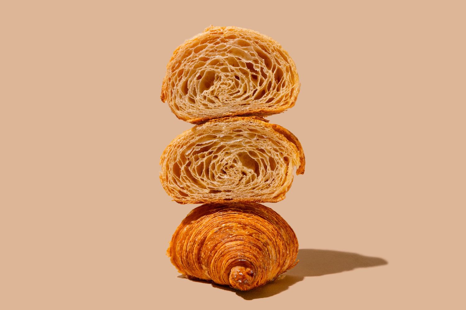 Cross-sections of croissants showing flaky layers on neutral background.