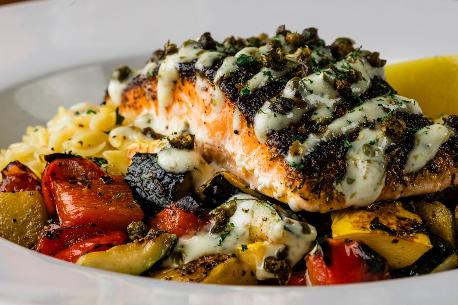 Grilled salmon topped with herbs served over roasted vegetables.