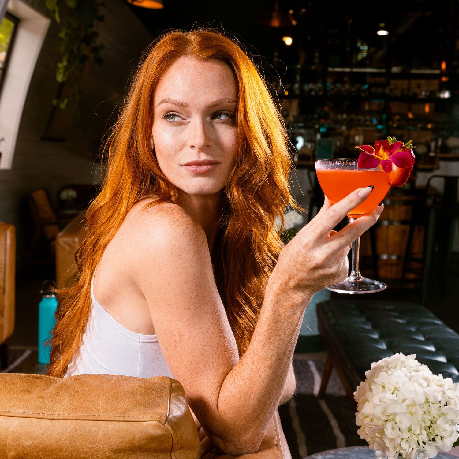 Lifestyle product photography showing cocktails and floral arrangements in warm evening setting.