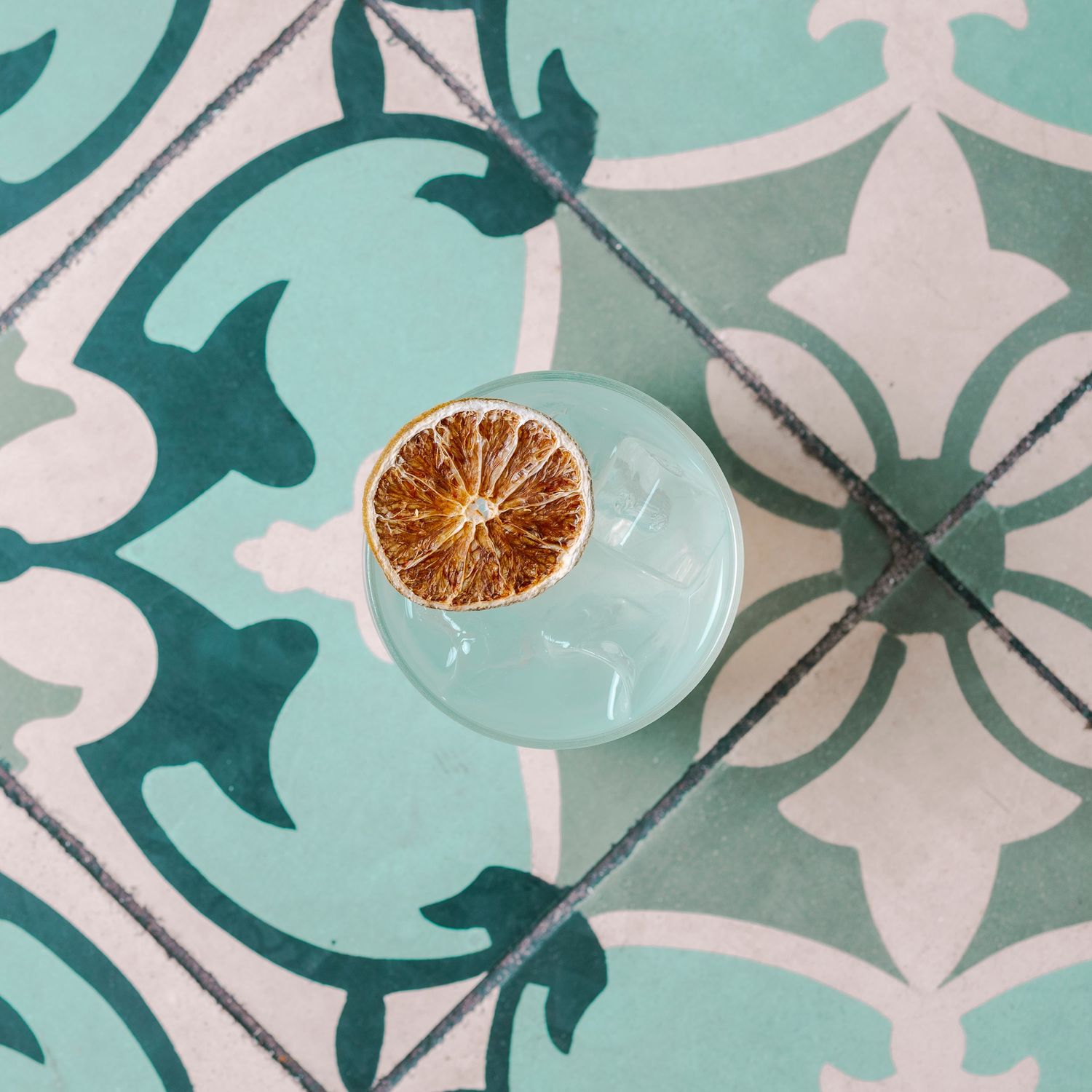 Teal and white geometric tile pattern with citrus fruit slices on a light background.