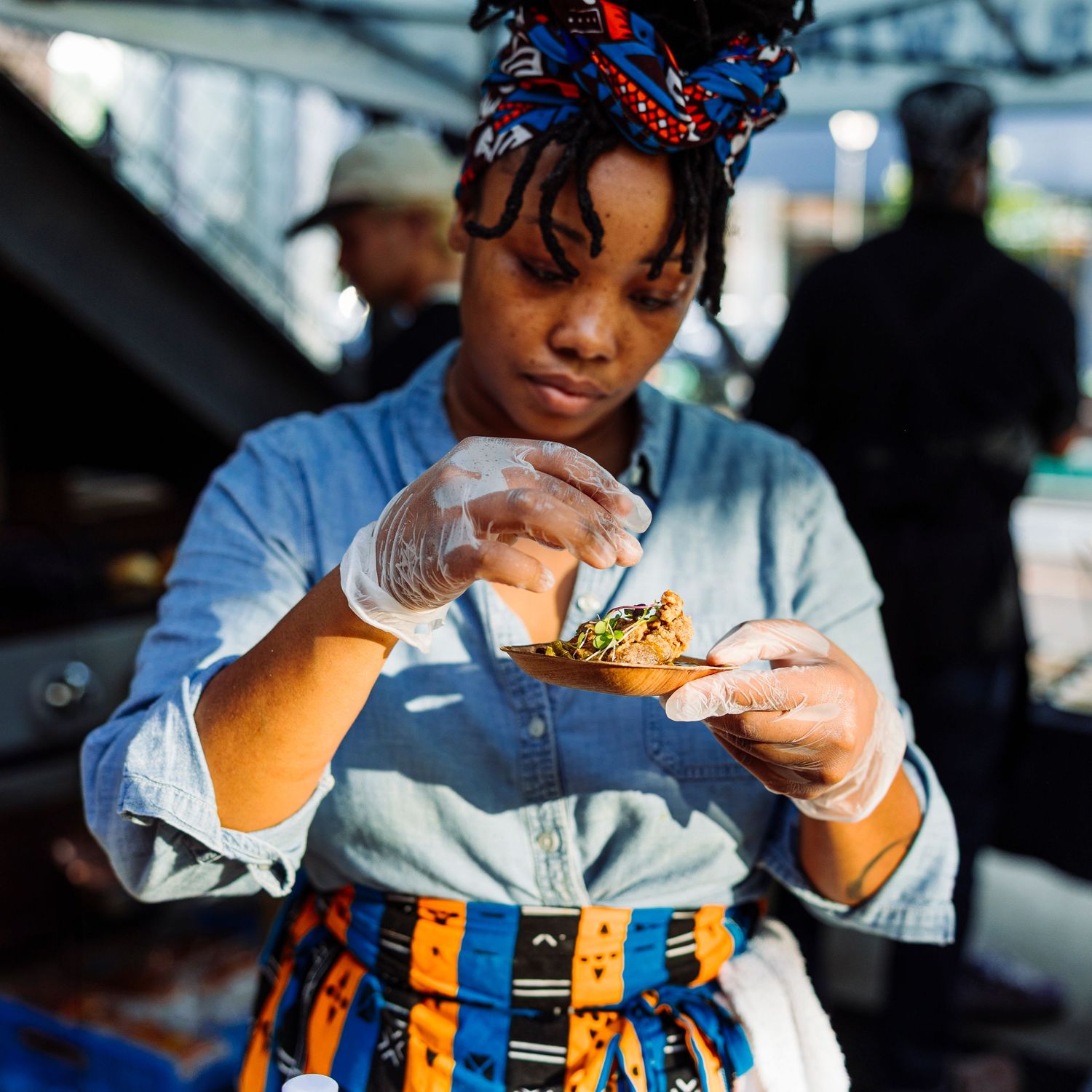 Food vendor preparing a fresh dish at an outdoor market.