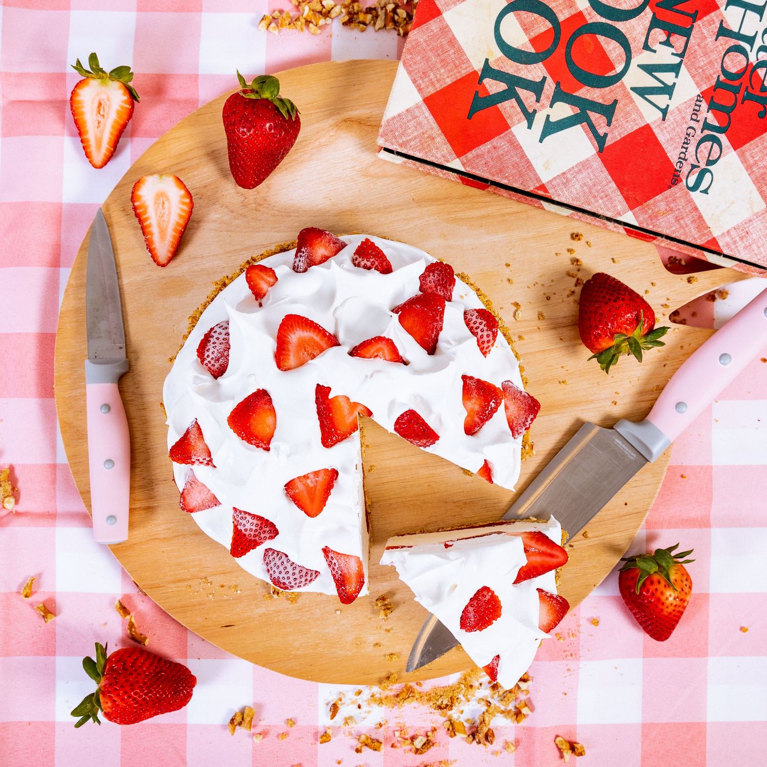 Fresh strawberries and Valentine's themed dessert wrappers on red checkered tablecloth.