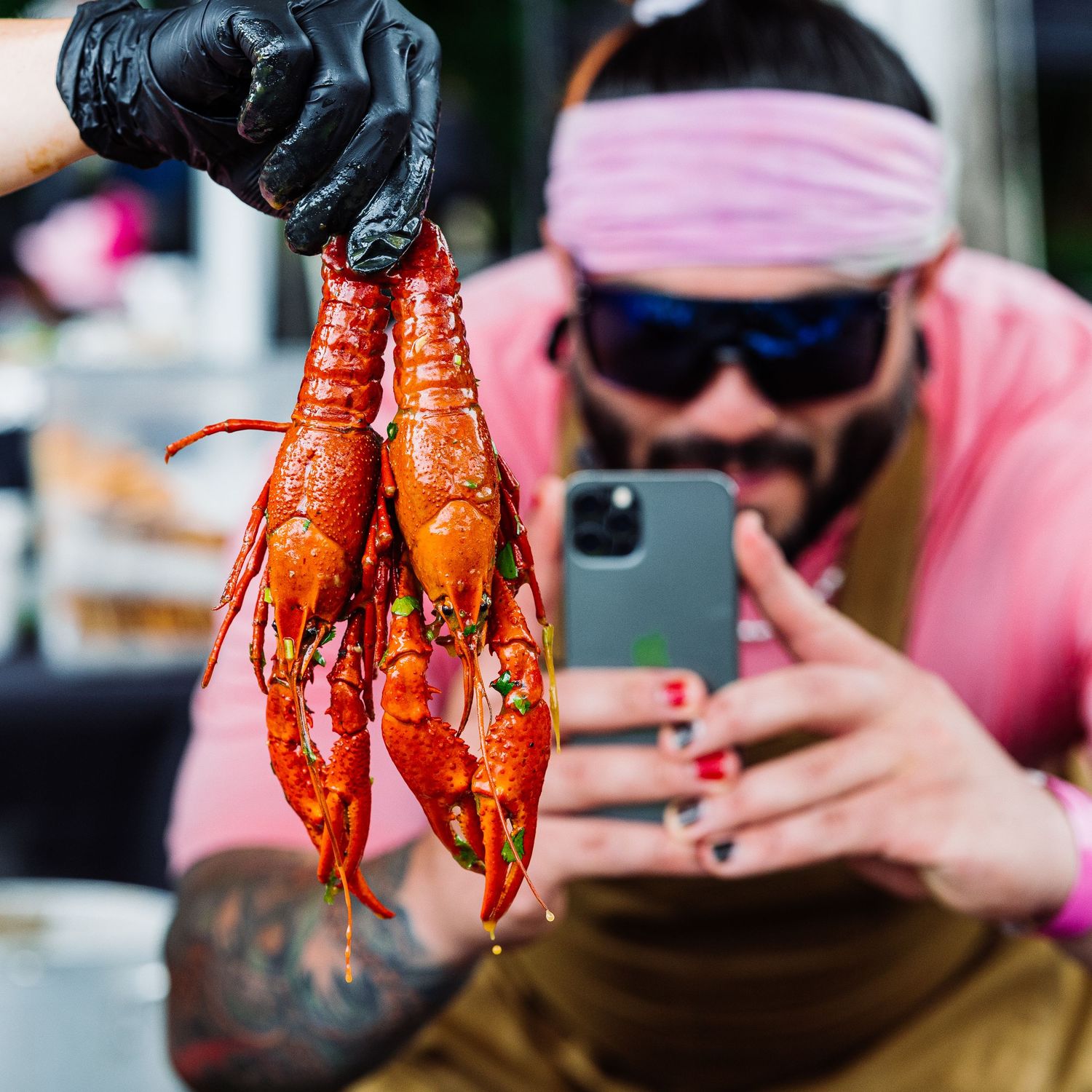 Freshly cooked red crawfish being displayed and photographed in a casual outdoor setting.