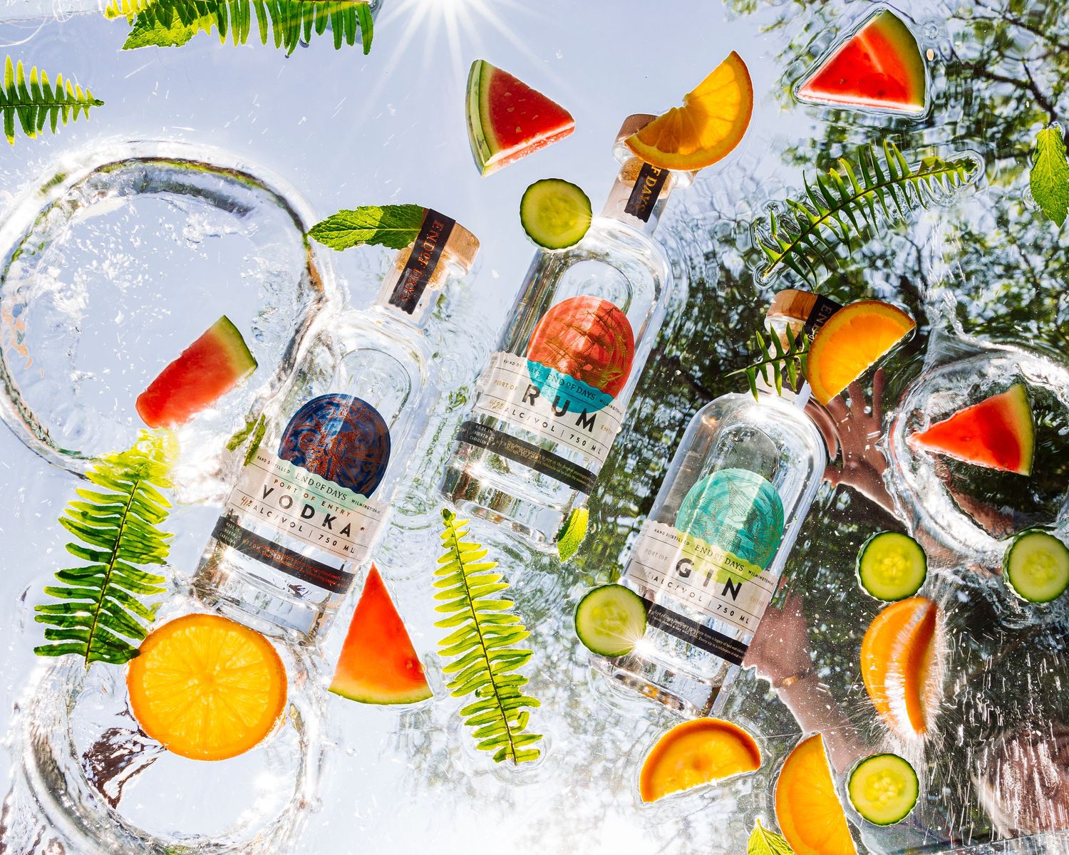 Refreshing summer cocktails with citrus and watermelon garnishes surrounded by tropical foliage.