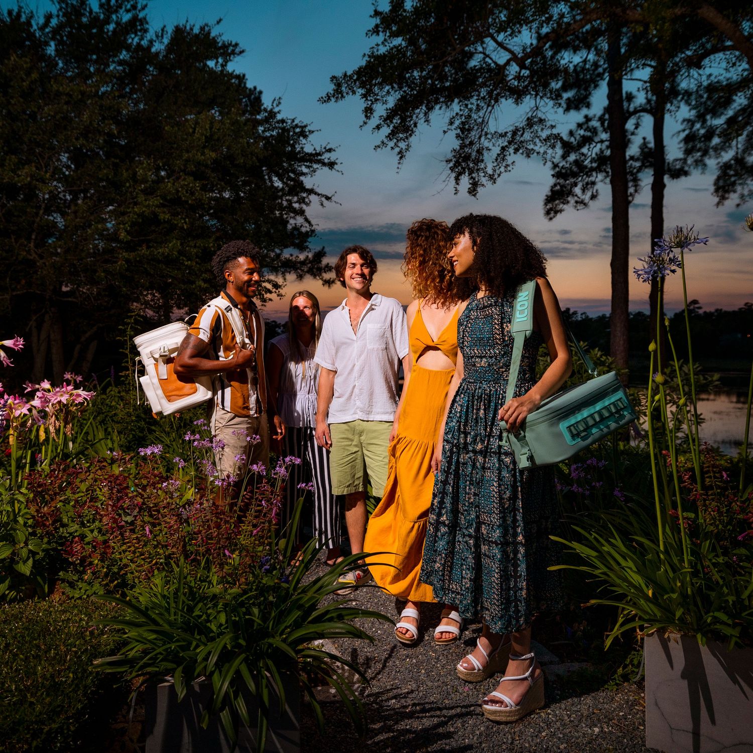 Group gathering at sunset on waterfront deck with flowers in foreground.