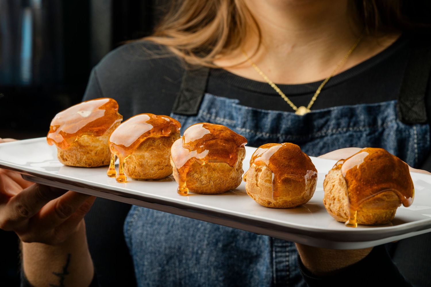 Row of golden brown sliders served on long white platter.