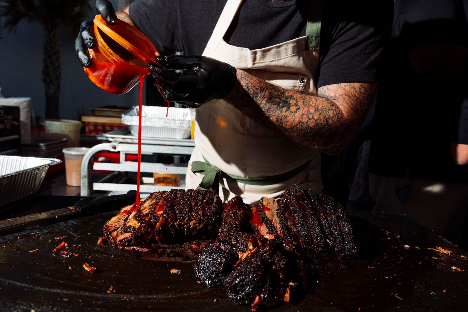 Close-up shot of smoked brisket being sliced on a wooden cutting board.
