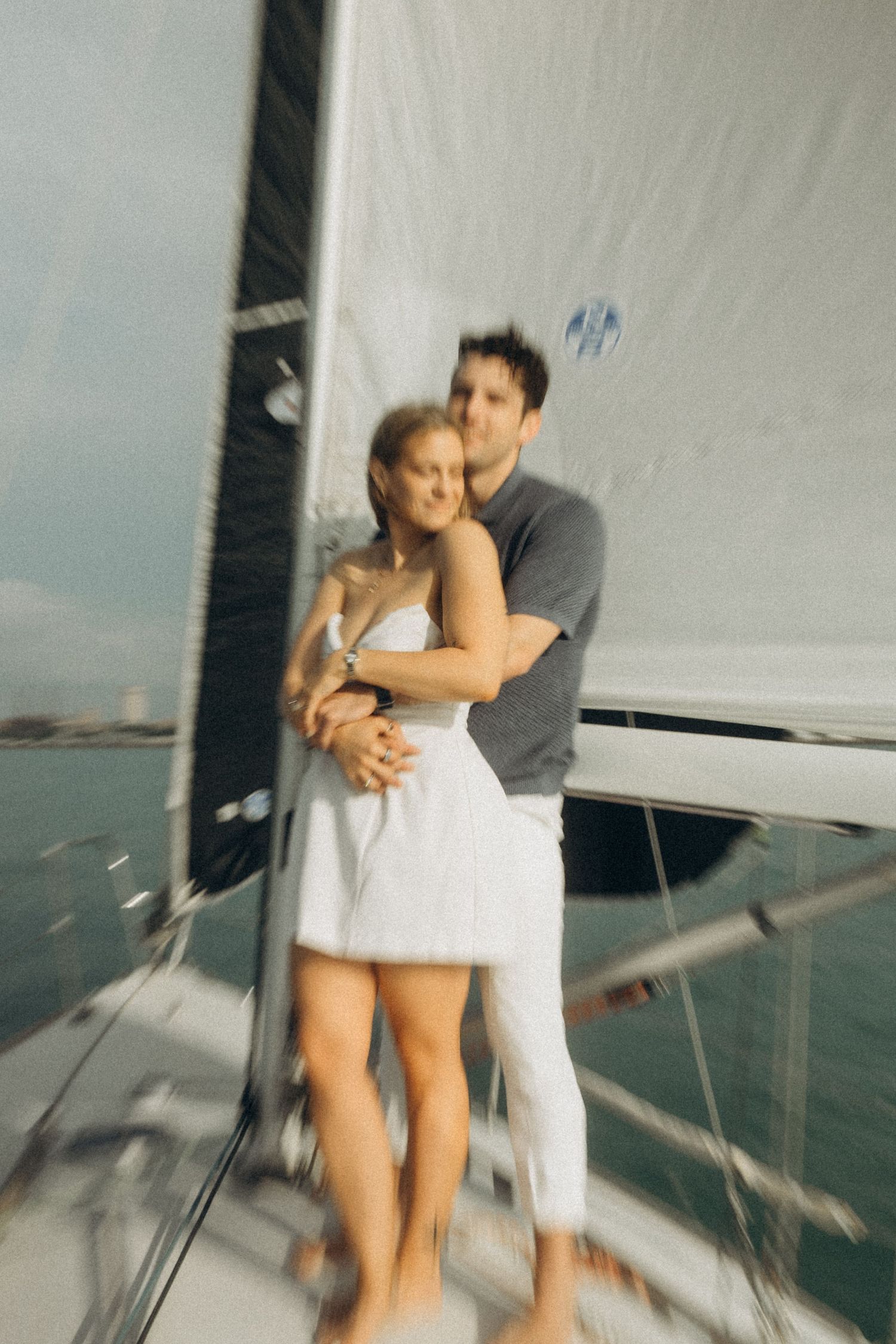 Blurry motion photographs of people on a sailboat deck in white attire.