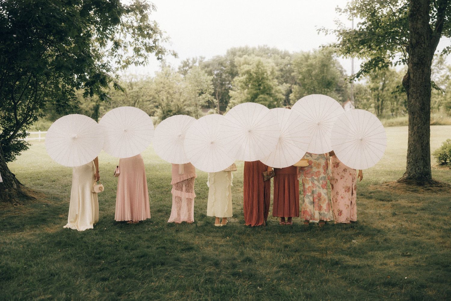 A row of vintage pink and white tents set up on a grassy hillside in natural lighting.