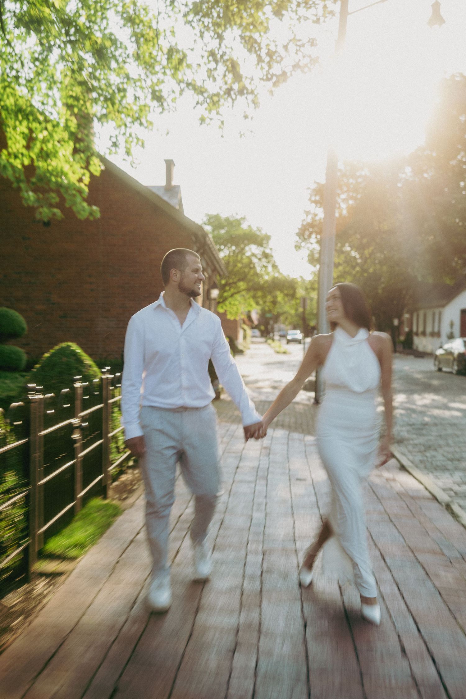 Couple dancing playfully on wooden boardwalk during sunset.