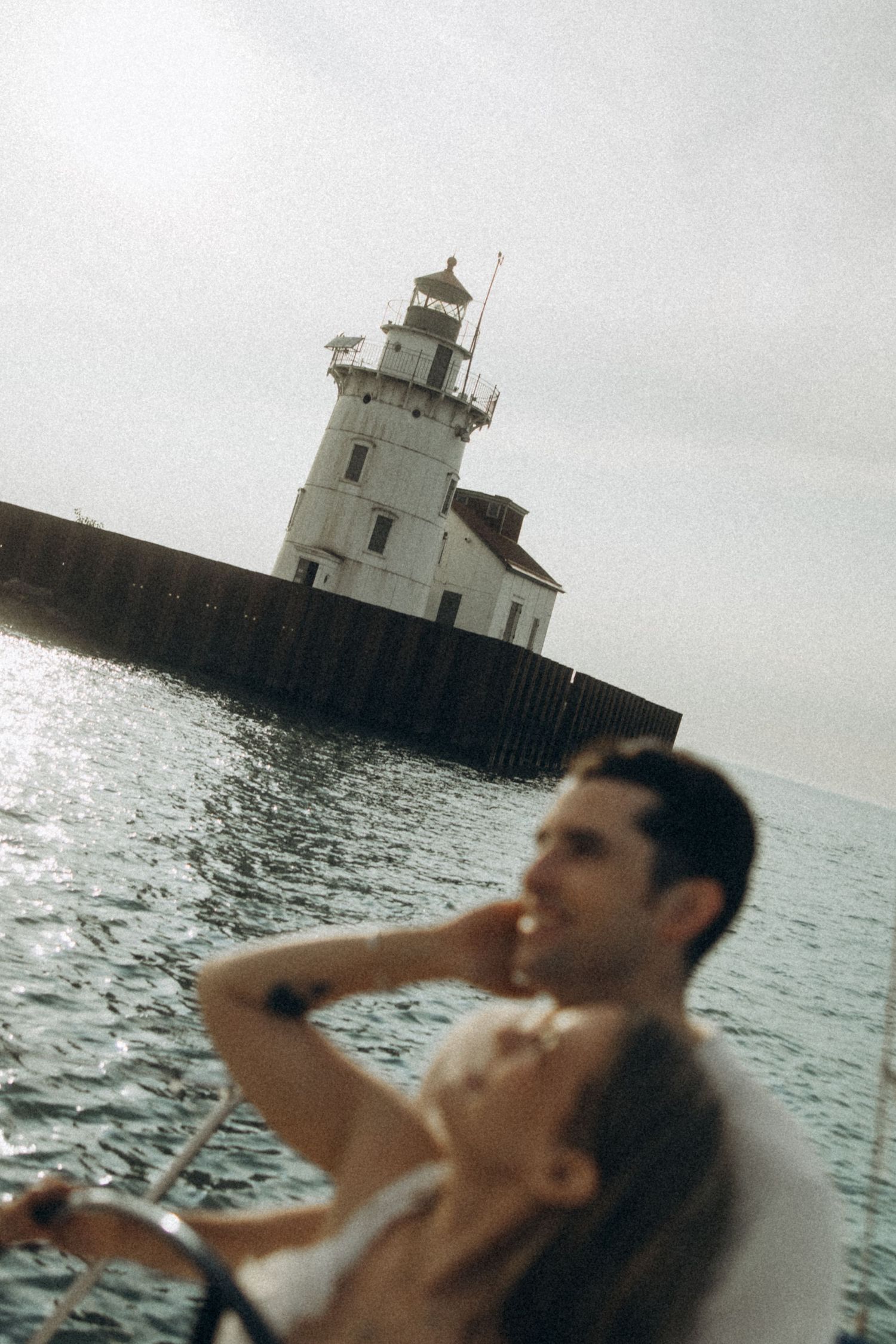 A lighthouse stands tall in the water against an overcast sky.