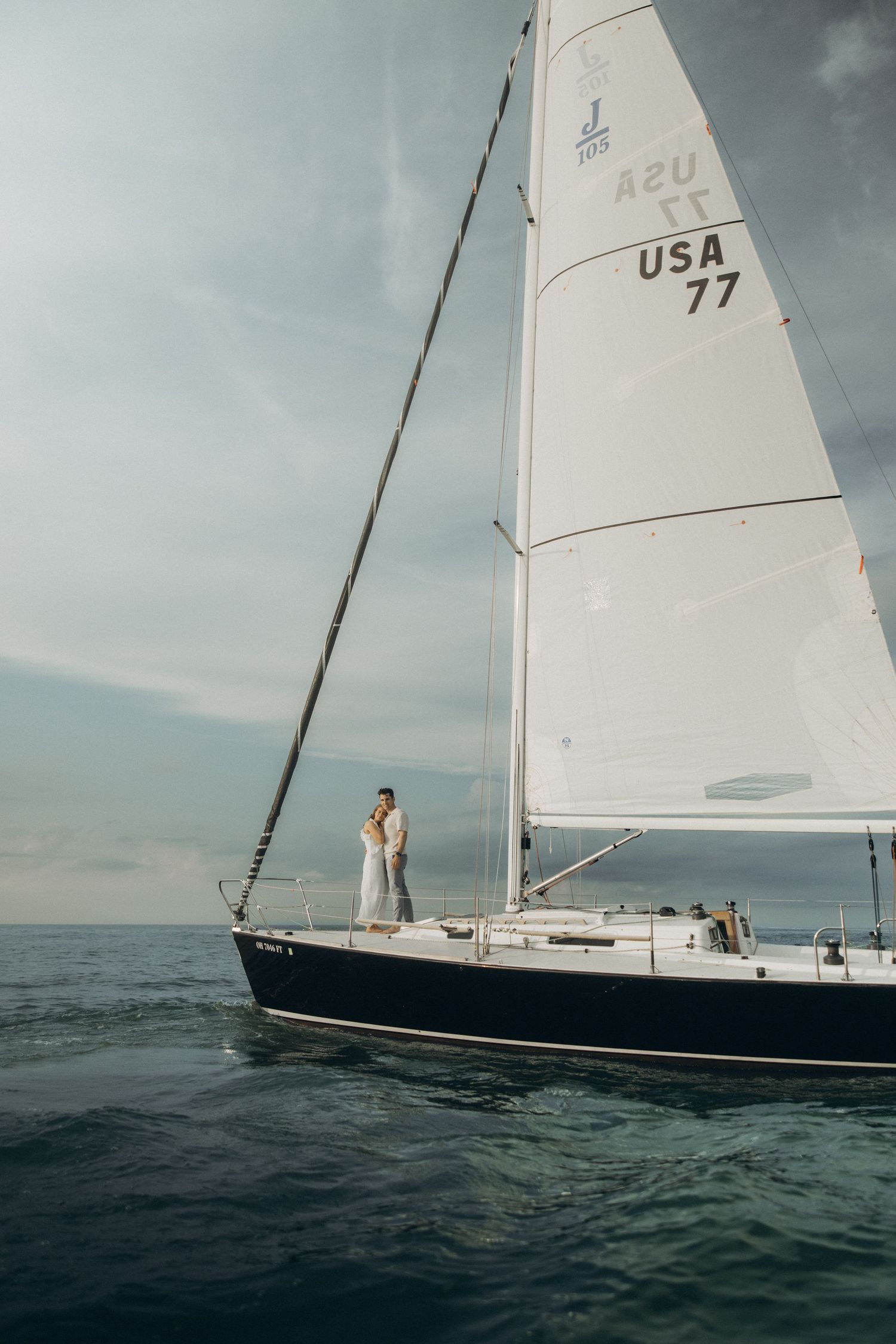 A sequence of four photos showing a sailboat with white sails gliding across dark ocean waters under moody skies.