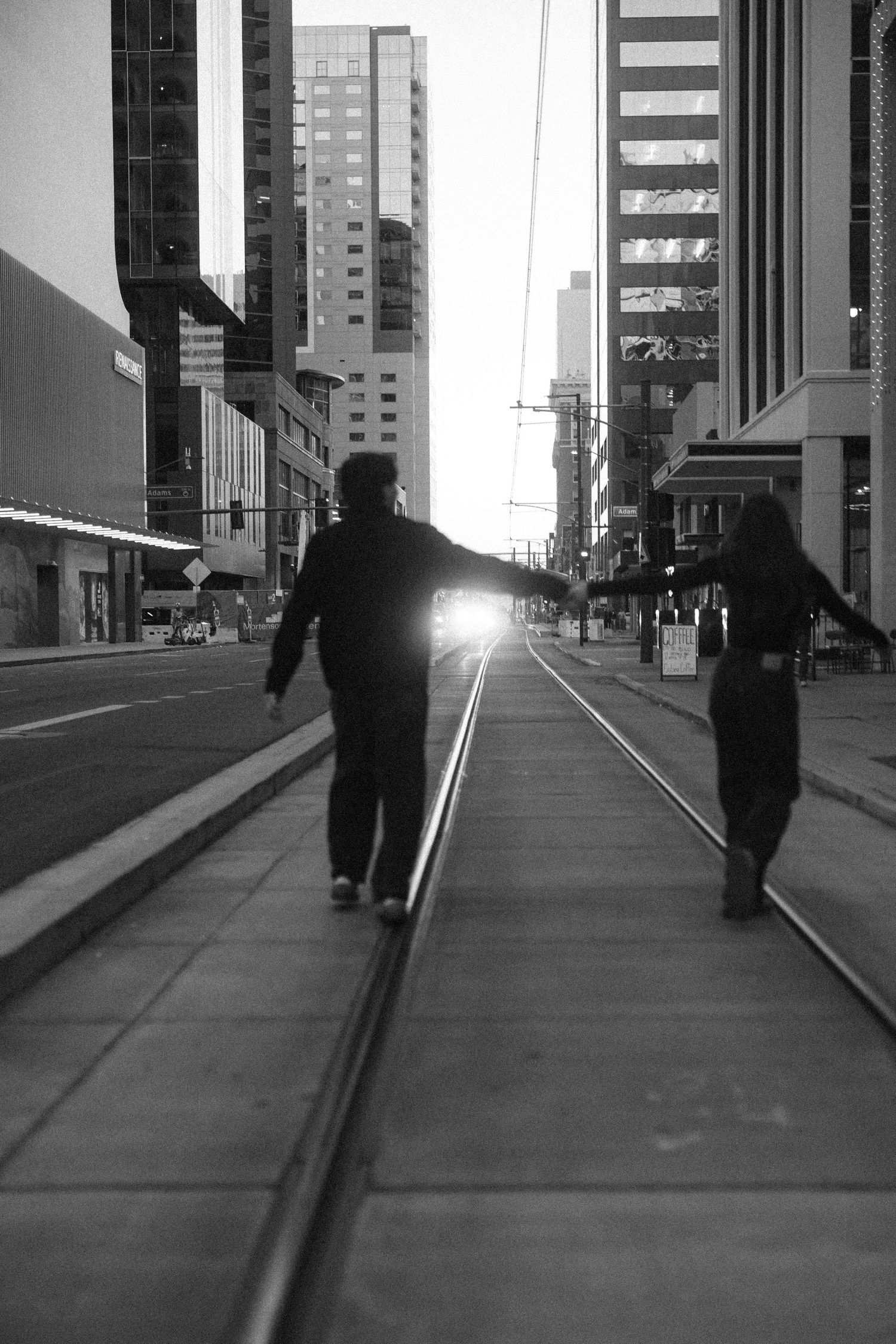A sequence of black and white photos showing a silhouetted figure walking along an urban sidewalk with tall buildings in background.