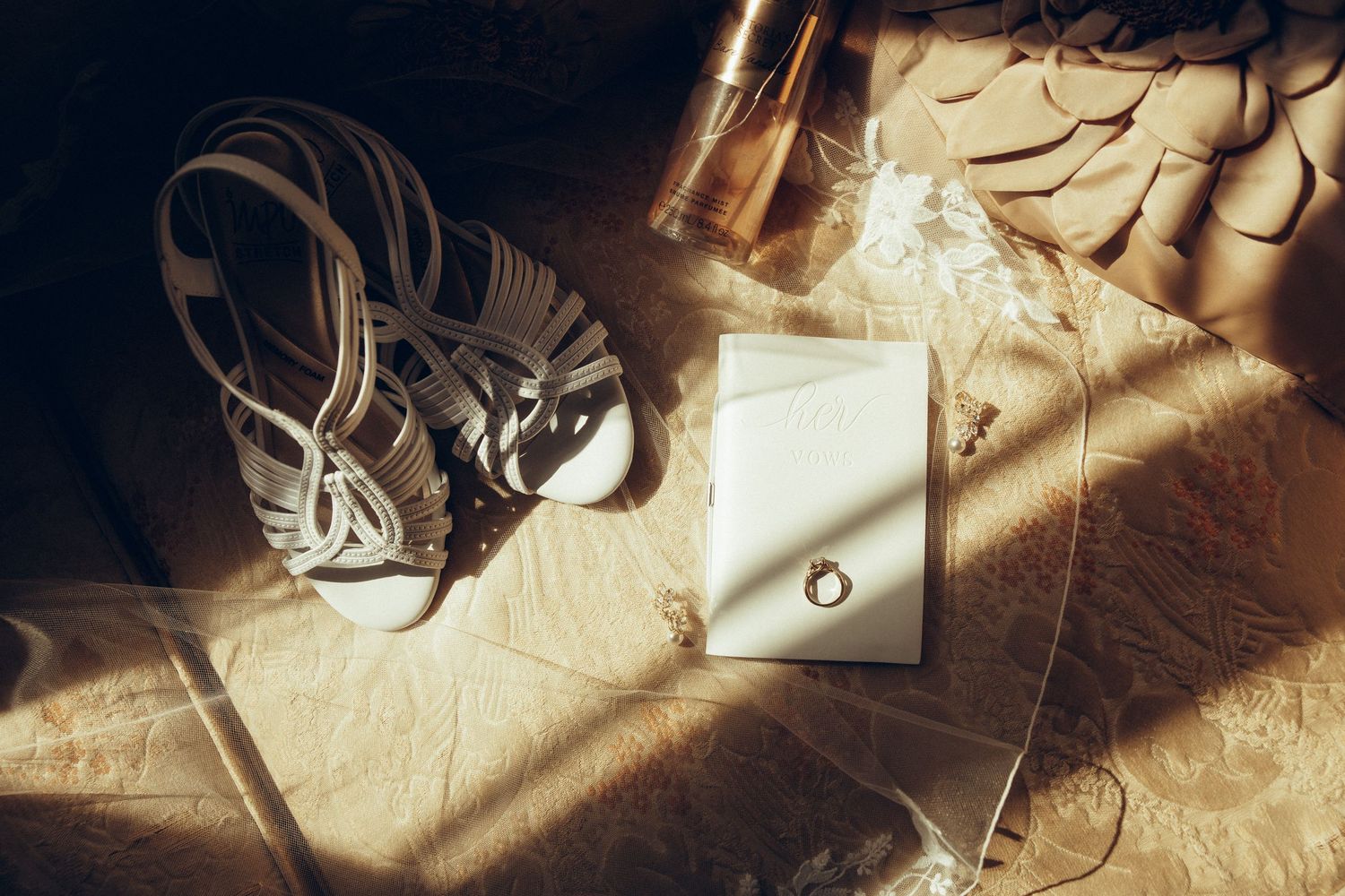 Sunlit wedding details and stationery arranged artistically on a rustic wooden surface.