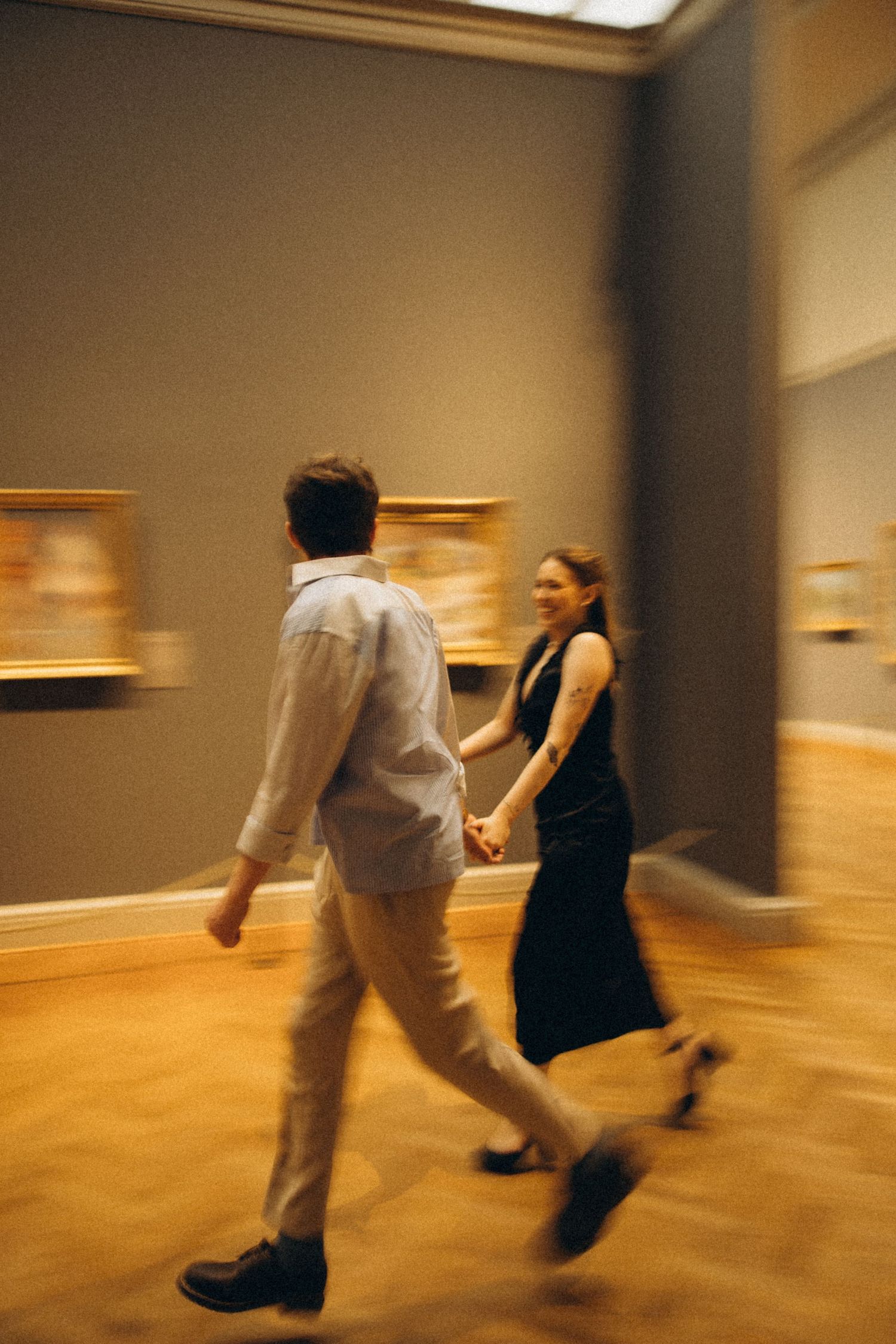 Motion-blurred figures dancing across a wooden gallery floor.