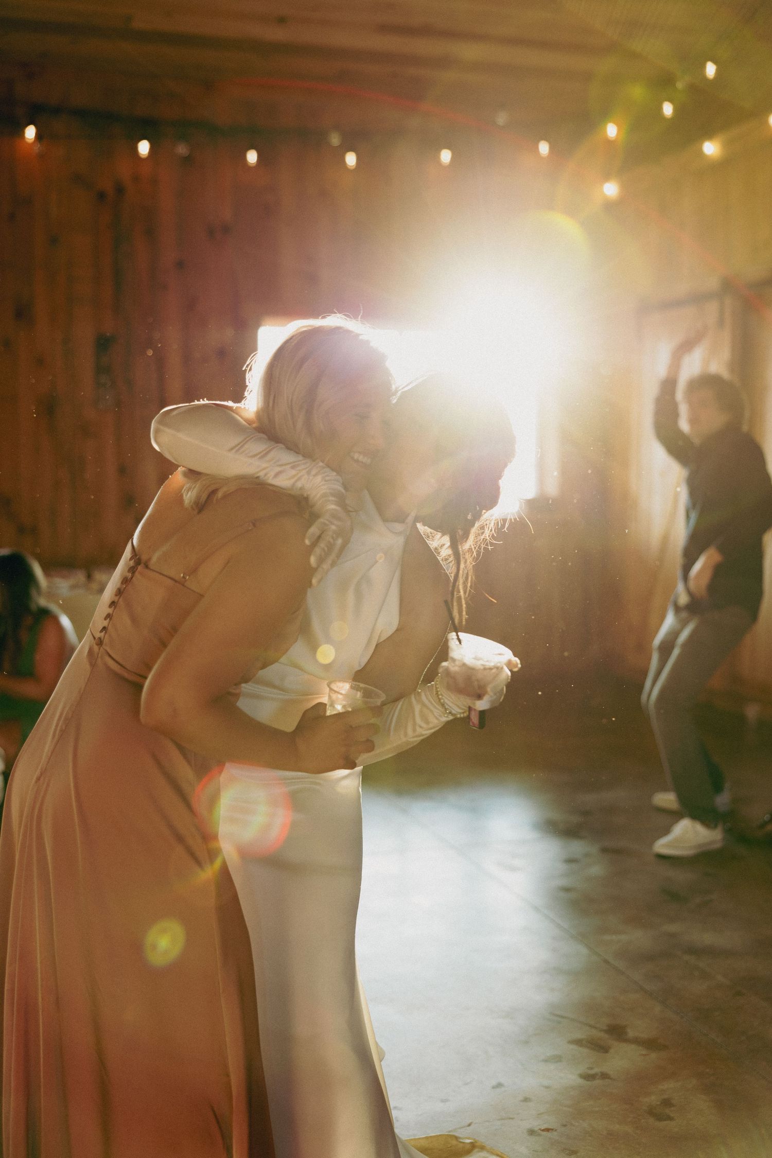 Dancing figures in a rustic barn illuminated by warm string lights.