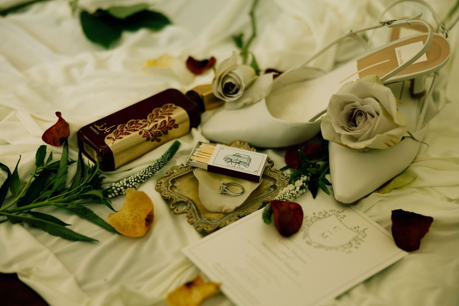 Wedding details including white roses and decorative elements arranged on a light surface.