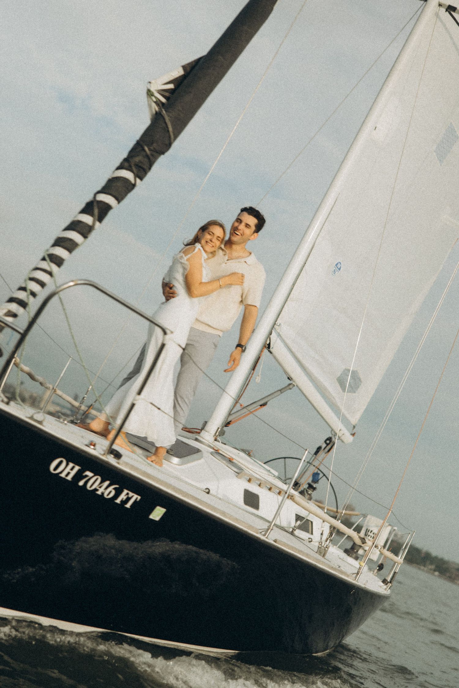 Couple enjoying a romantic moment on a sailboat deck during a sunny day.
