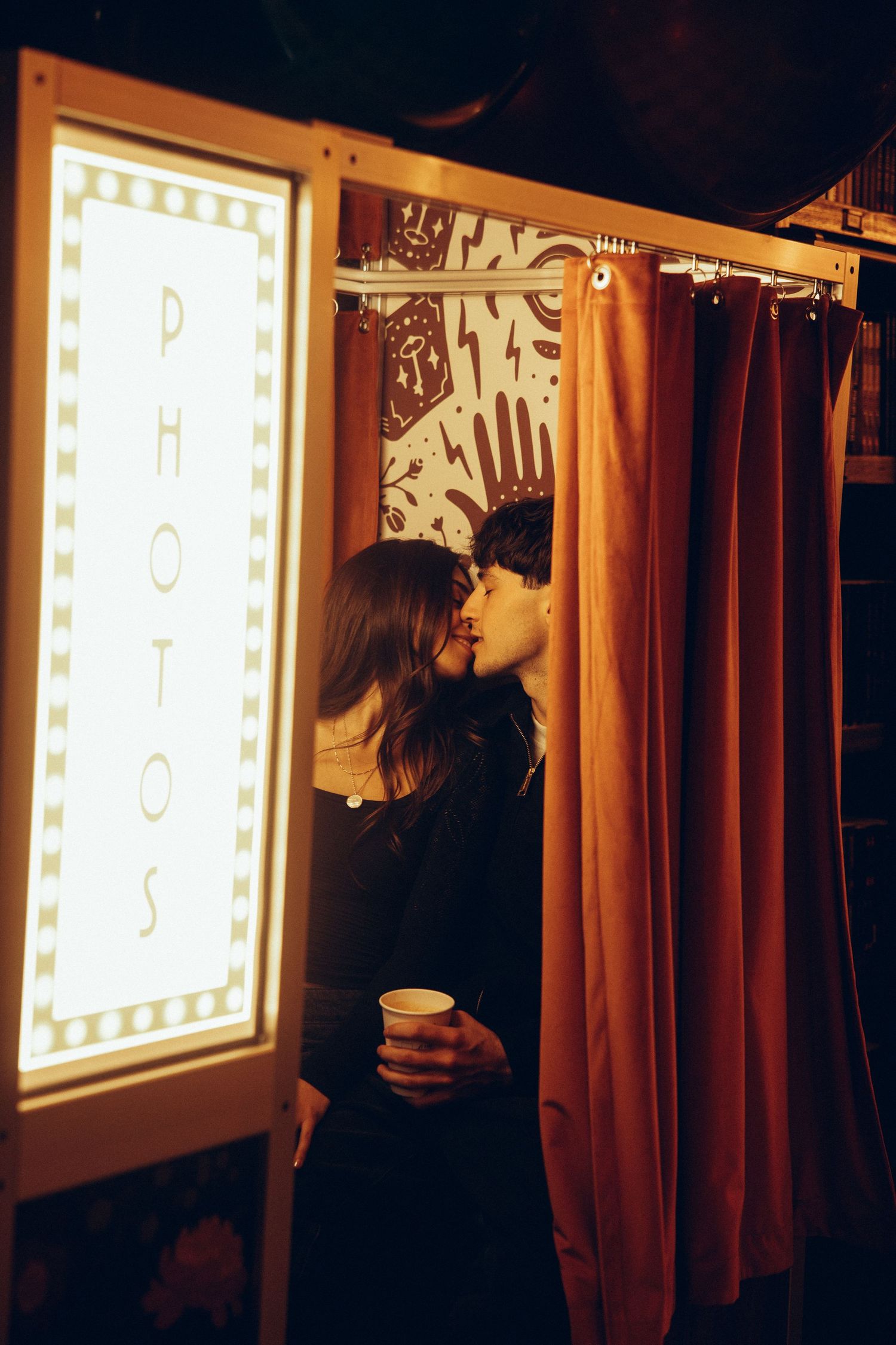 Silhouette against illuminated display panels with brown curtains in a dark room.