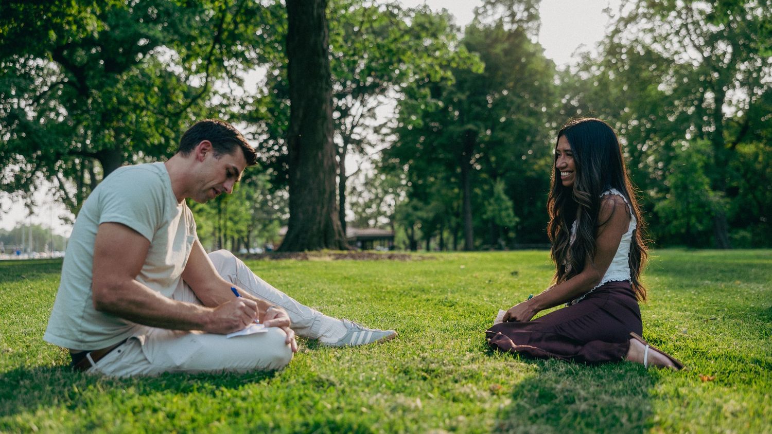 Couple relaxing together on grass in a sunny park setting.