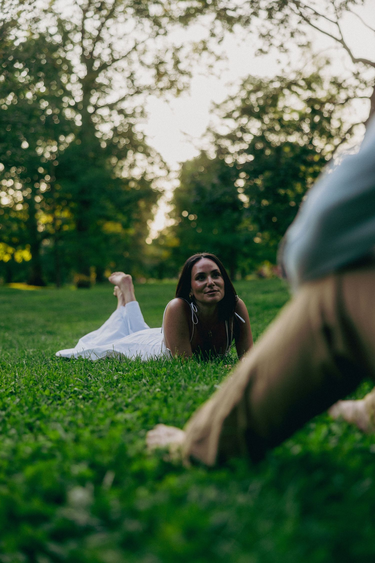Couple lying in green grass during a romantic outdoor photoshoot.