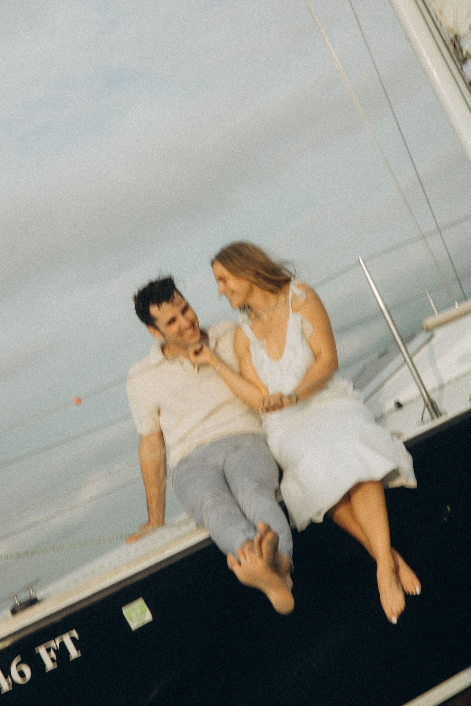 Two people relax on the deck of a sailboat on a sunny afternoon.