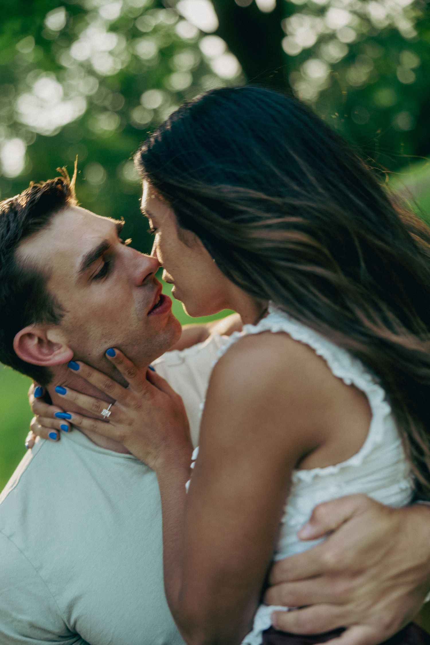 Romantic couple sharing intimate moments in a sunlit park.