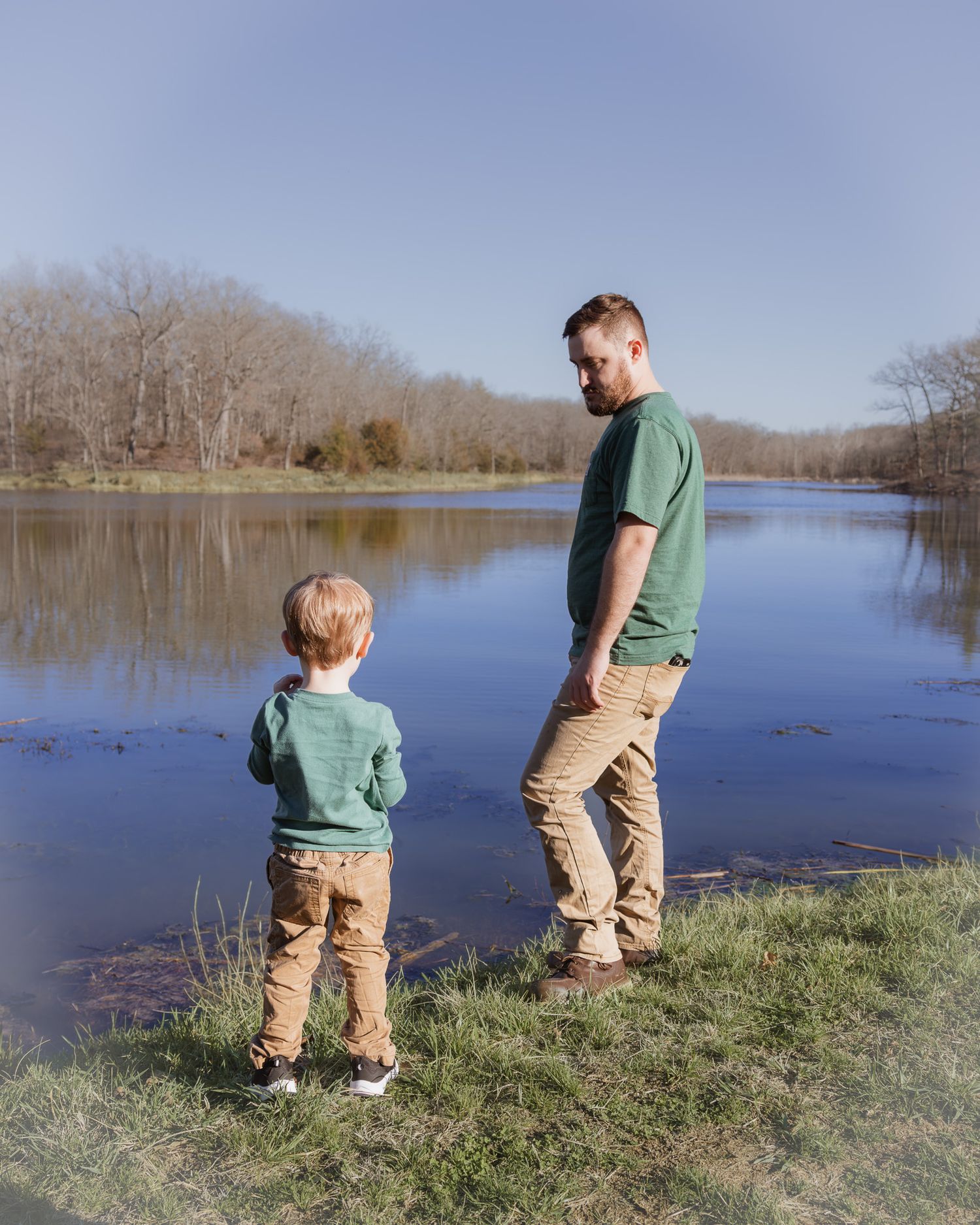 Father and child standing by a serene lake during a family photo session.