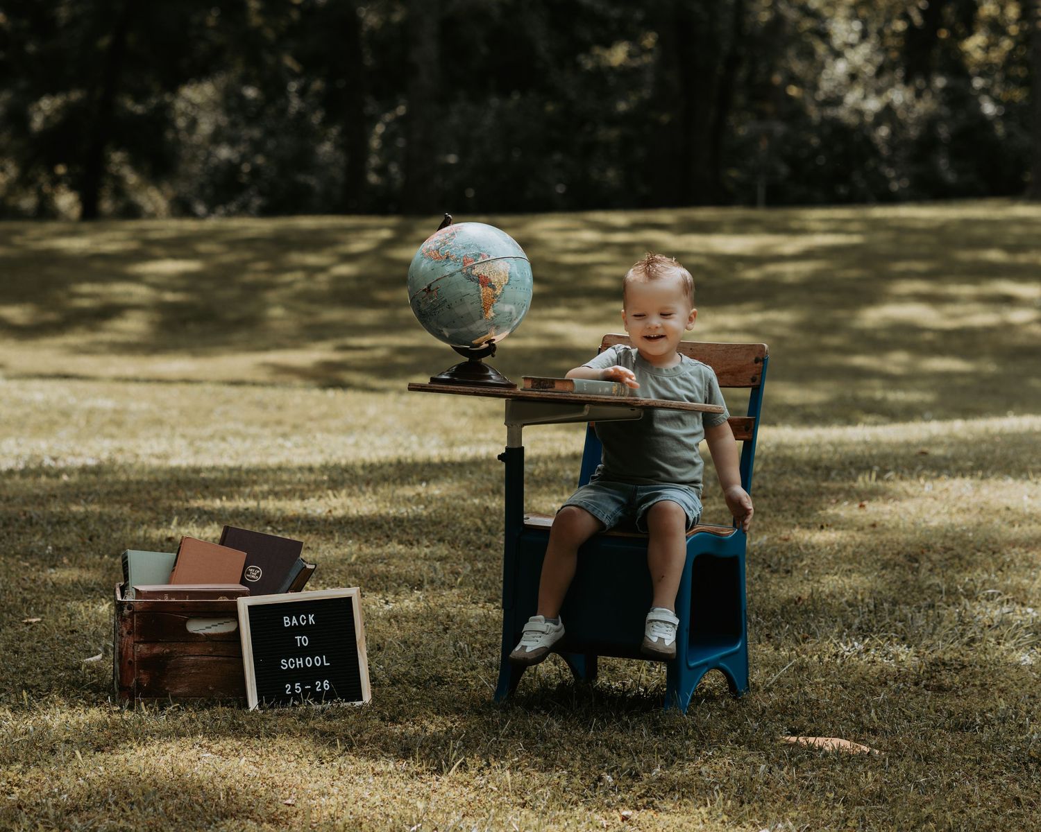A series of outdoor milestone photos showing a young child sitting on grass with a small chalkboard sign.