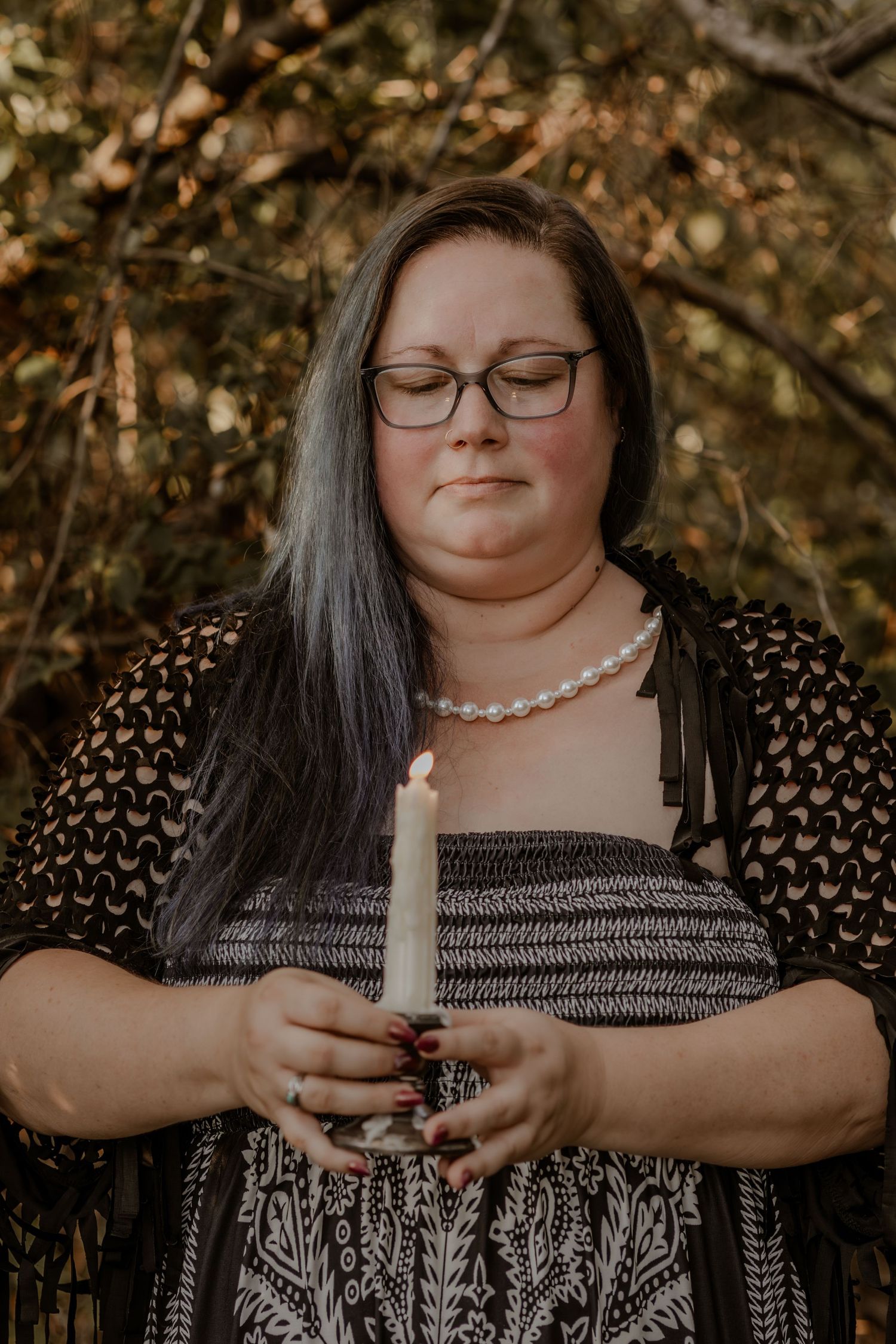 Person holding a white candle during an outdoor autumn ceremony.
