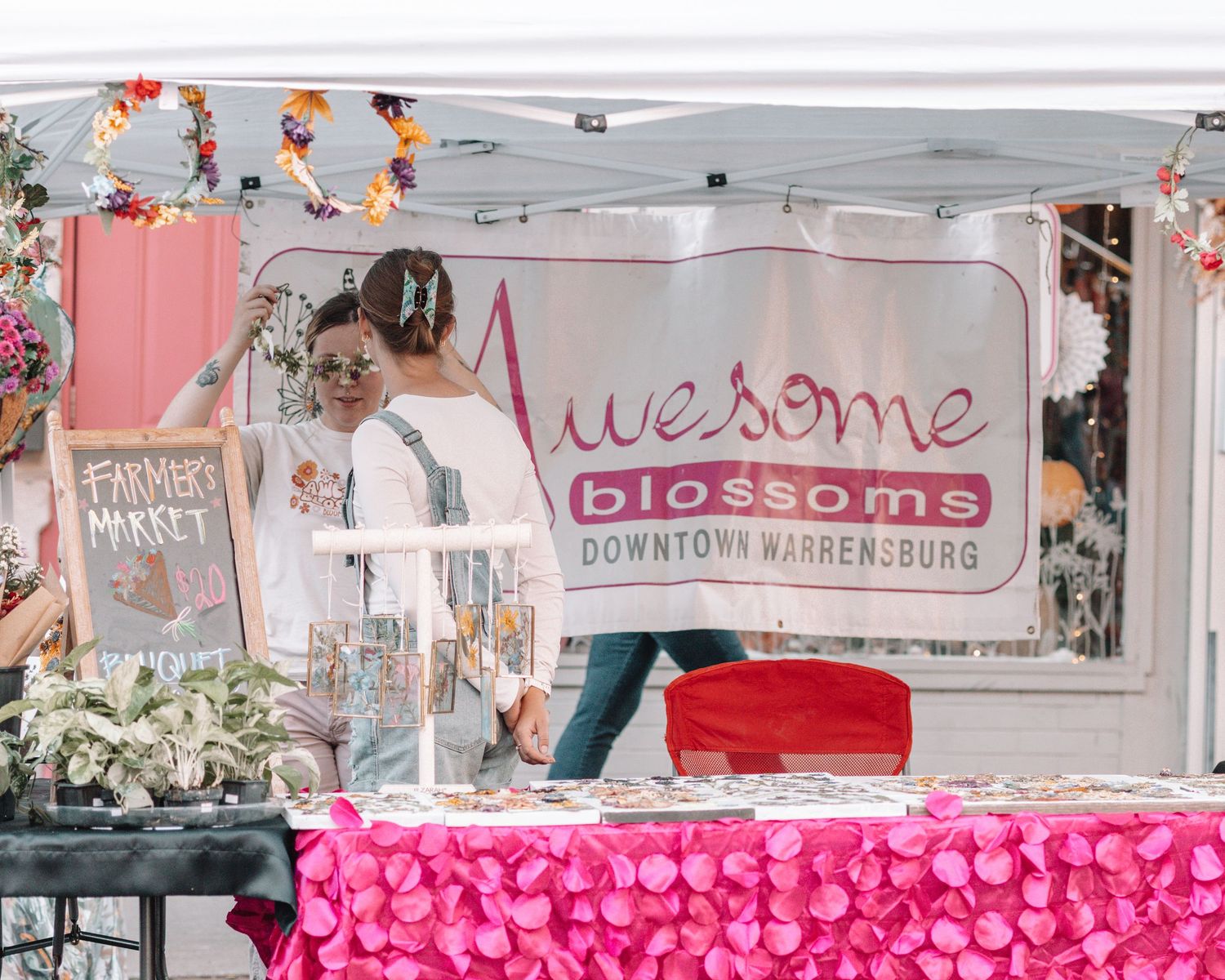 Pink-decorated vendor booth with 'Awesome' and 'Blossoms' signage at an outdoor market.