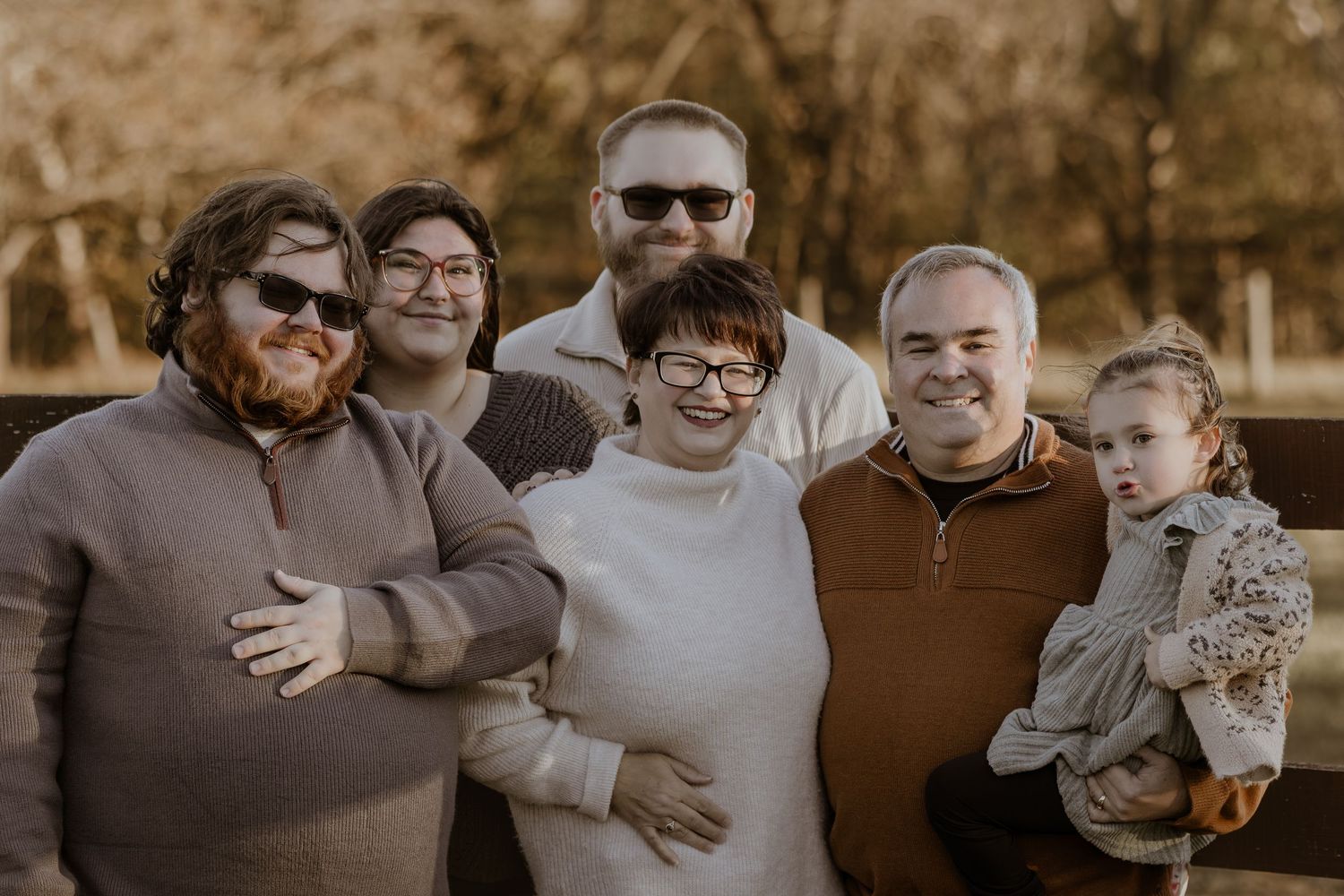 A loving family embraces and smiles together during an outdoor autumn photoshoot.