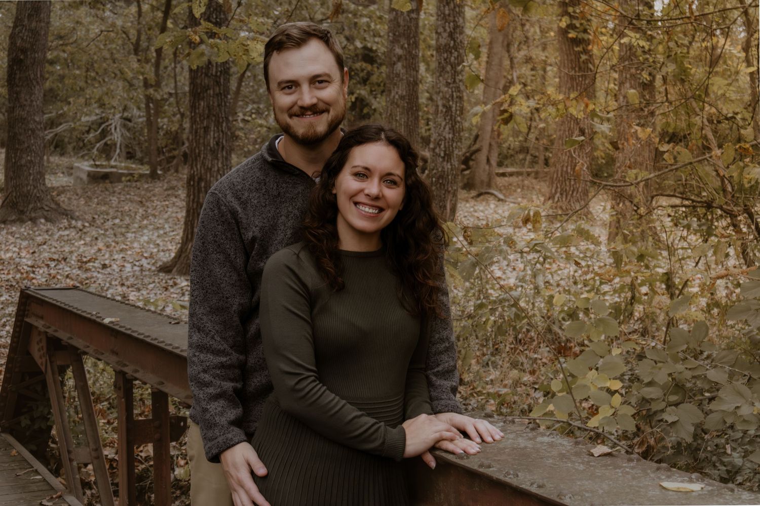 Family photoshoot on a rustic wooden bridge surrounded by fall foliage.