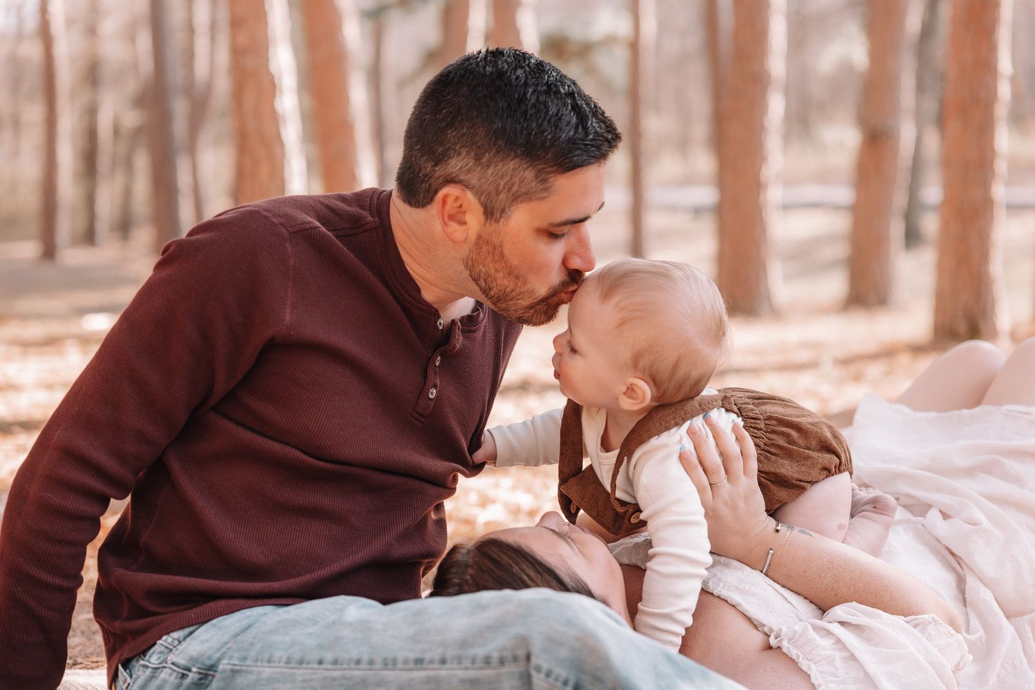 An intimate moment between parent and child sitting on blanket in wooded setting.