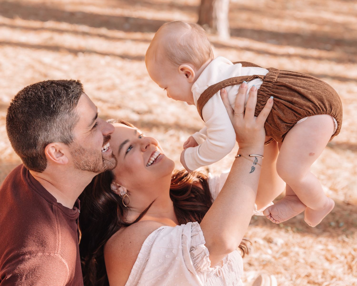 Family sharing joyful moments together during outdoor photo session in wooded setting.