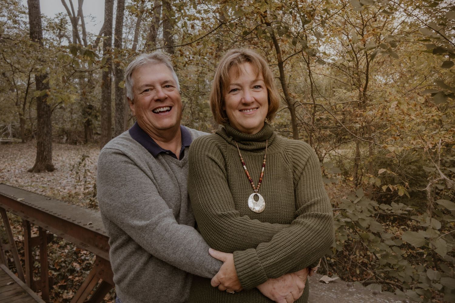 A couple sharing a tender moment together outdoors with golden sunlight filtering through trees.