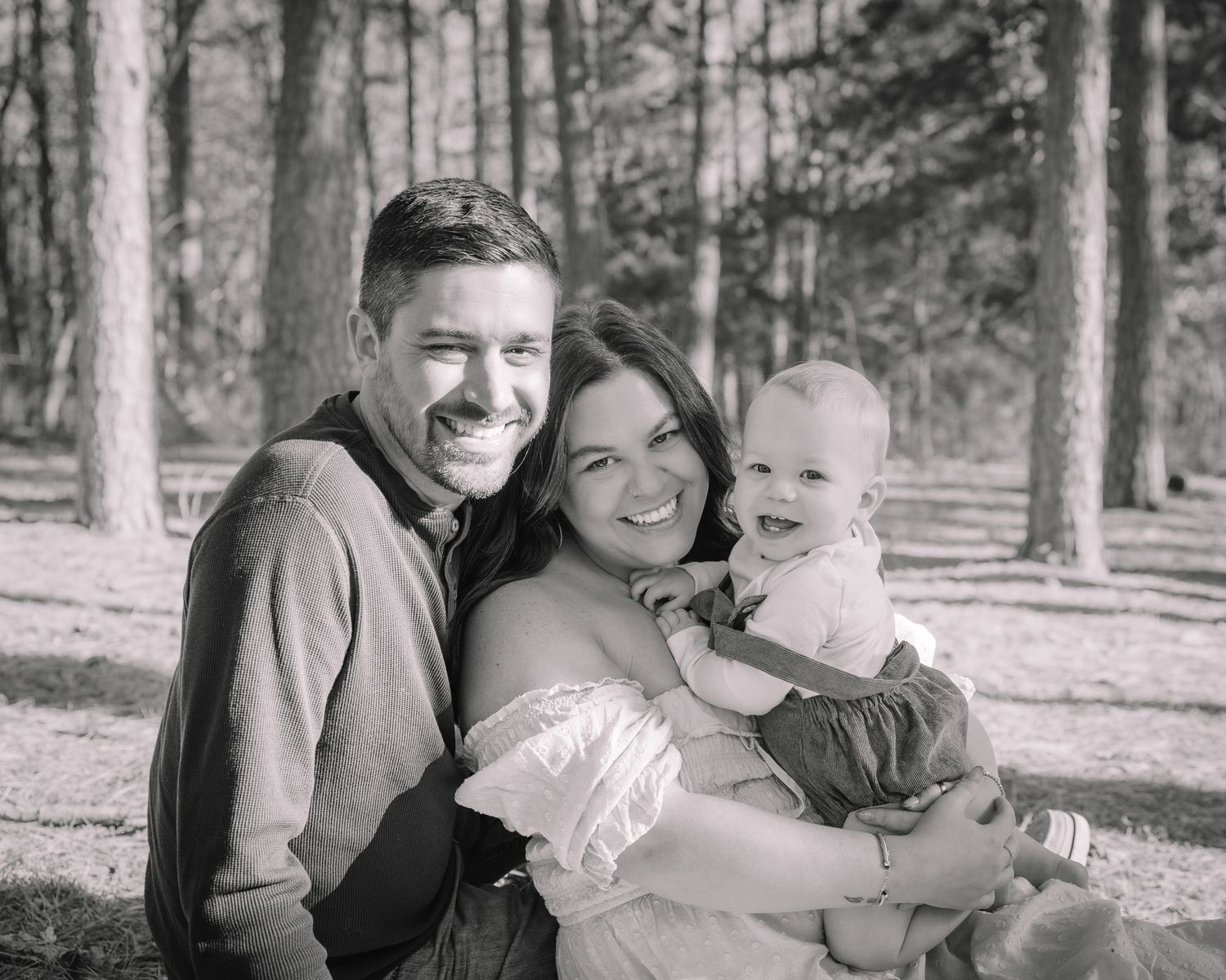 Black and white family photos capturing candid moments of togetherness in a forest setting.