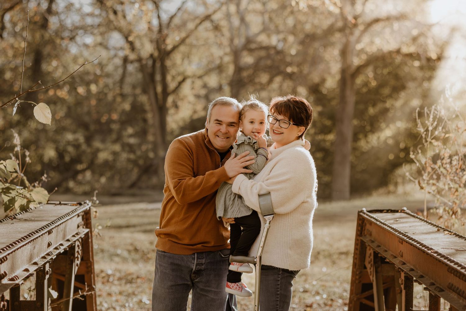 Family enjoying a tender moment together during a golden hour photoshoot on rustic wooden railroad tracks.
