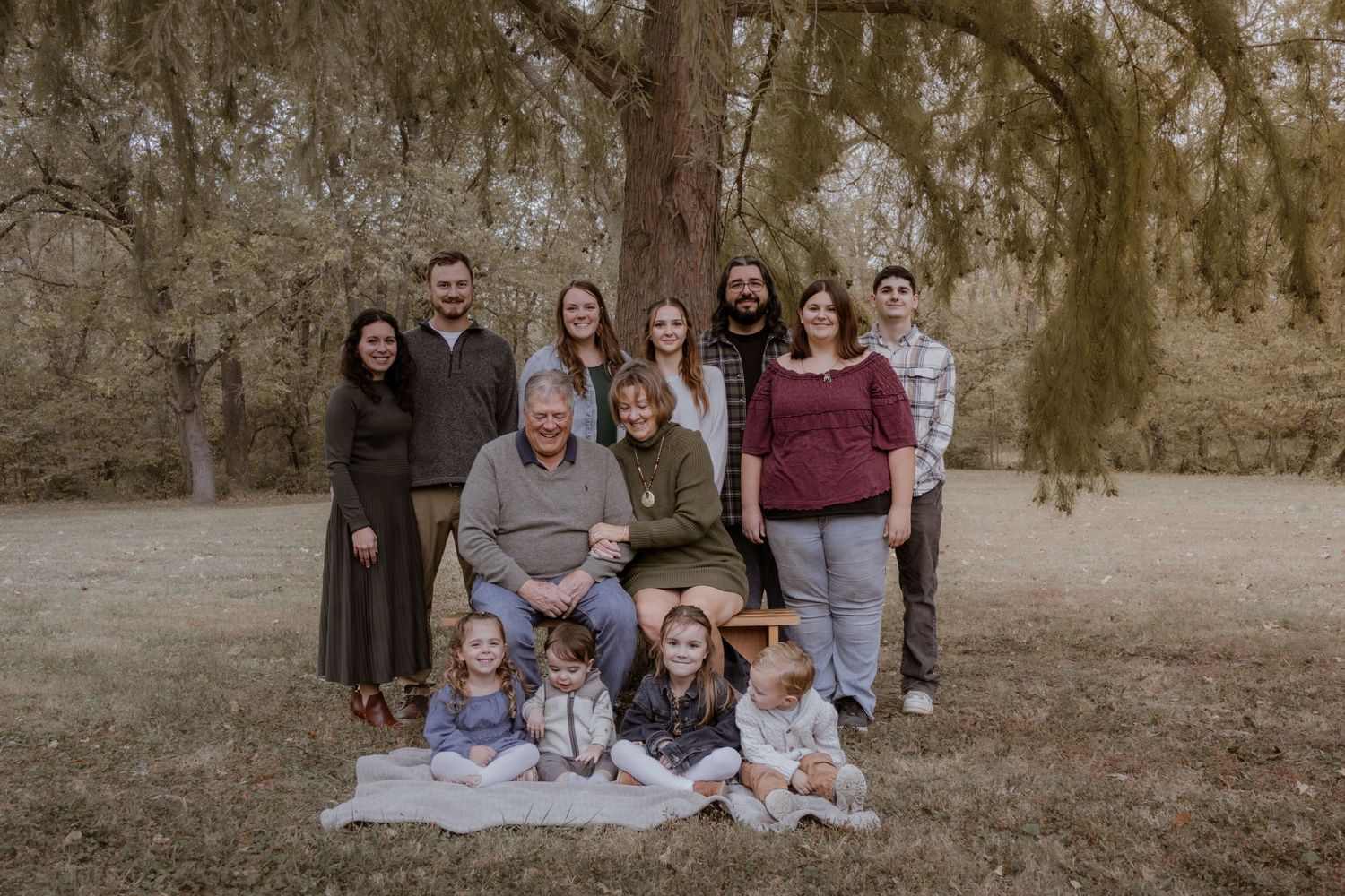 A series of outdoor family portrait photos taken in a natural setting with warm autumn lighting and rustic scenery.