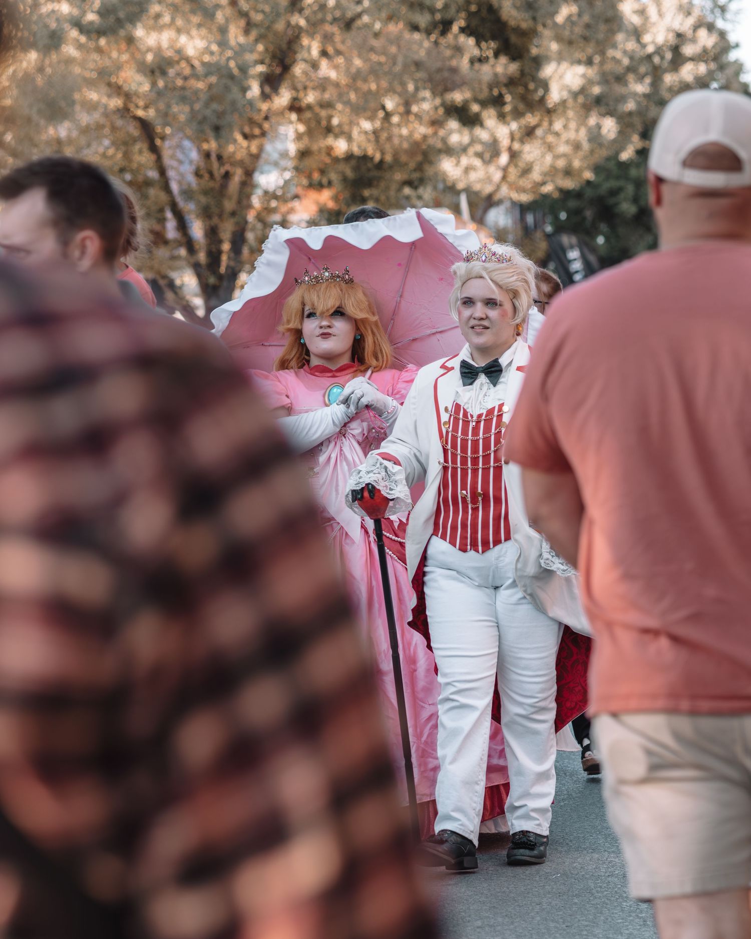 People in matching white and red striped outfits walking at an outdoor festival.