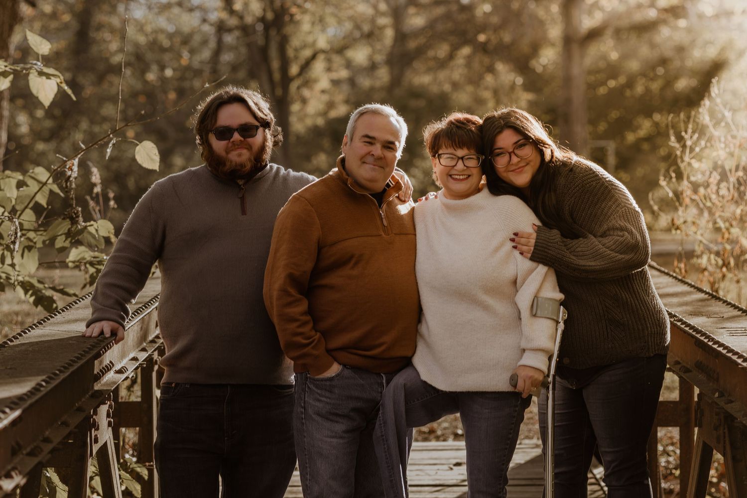 A family poses together outdoors during golden hour in a warm autumn setting.