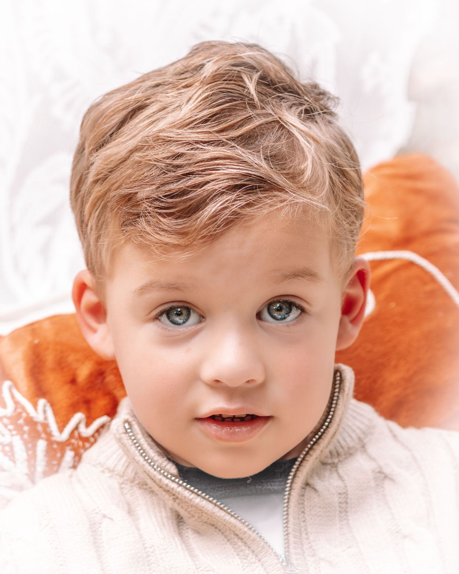 Close-up portraits of a young child with bright blue eyes against a white background.