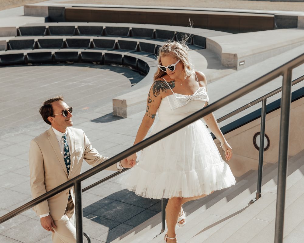 Wedding couple creates dynamic poses along modern outdoor steps and railing.
