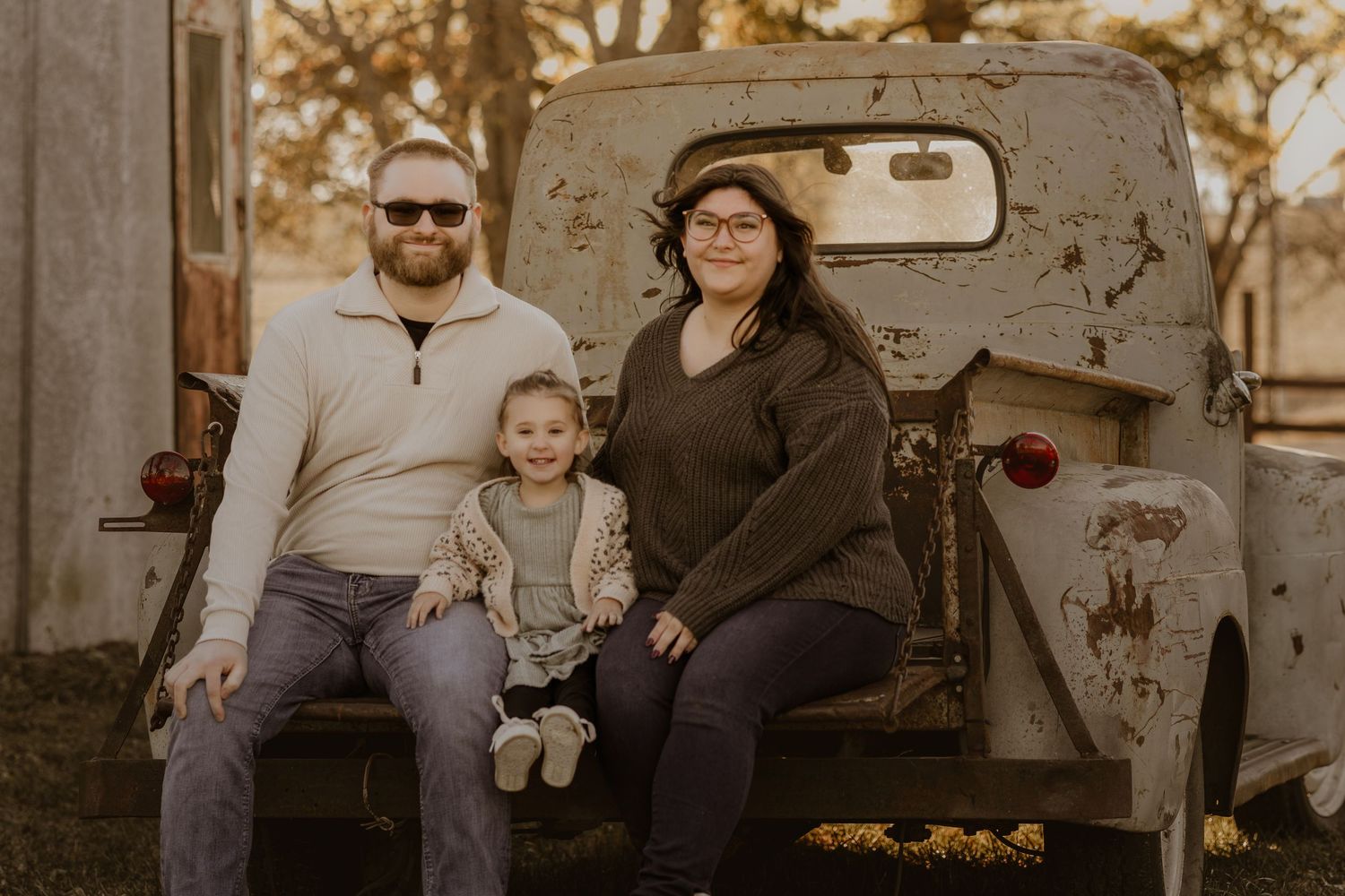 Family poses together near a vintage truck during sunset with warm autumn colors.