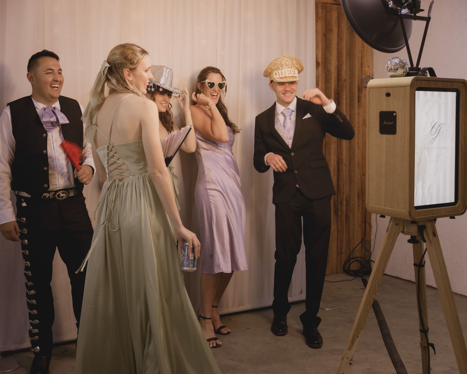 Wedding guests laughing and posing at a photo booth during a fun indoor reception celebration.
