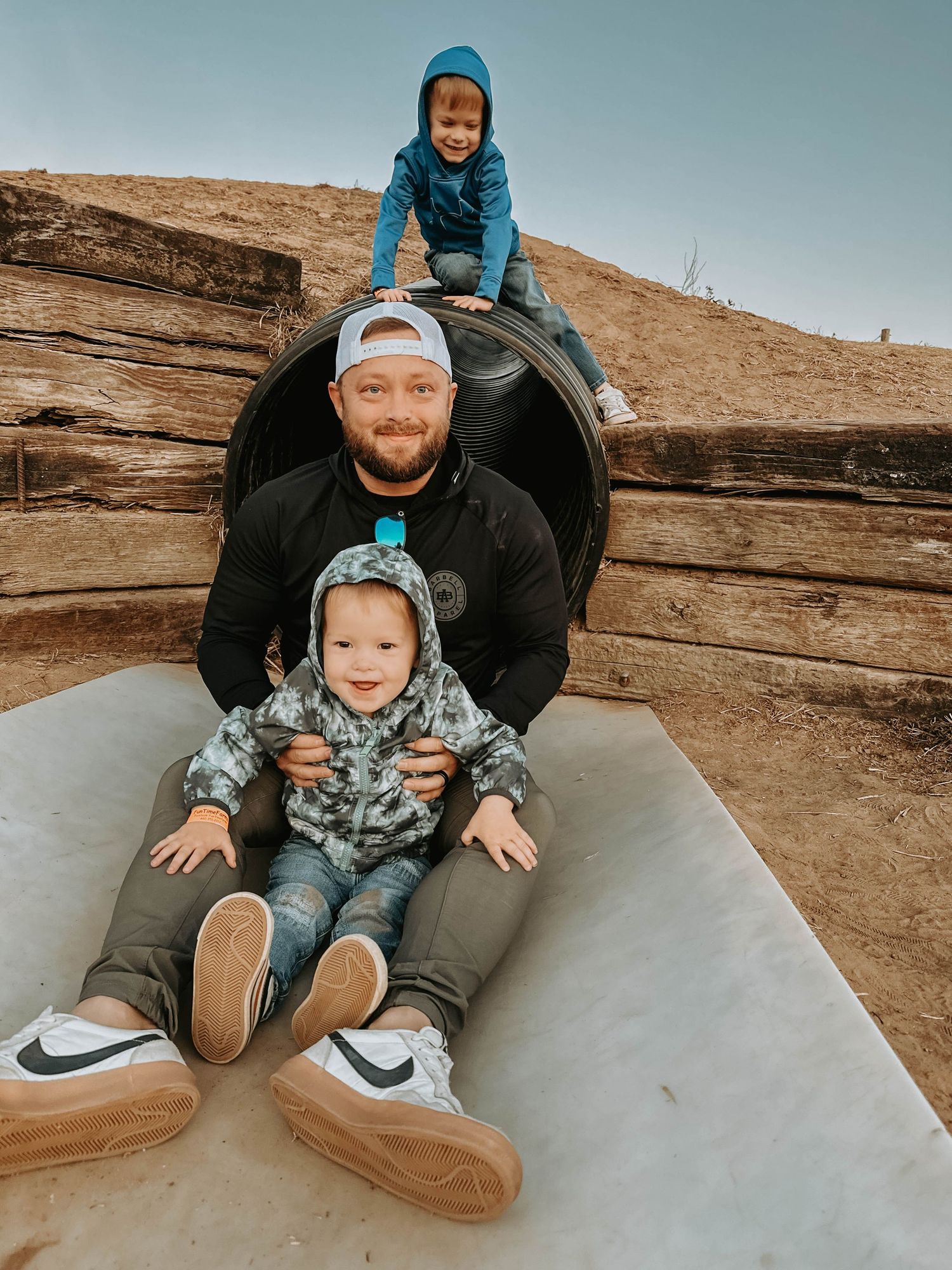 Parent and child sitting together on a rock formation in an outdoor desert setting, capturing a candid family moment.